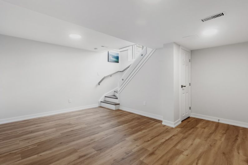 Attic Renovation - an empty room with a staircase and hard wood floors