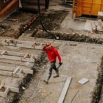 Contractor - man in red jacket and black pants walking on gray concrete stairs