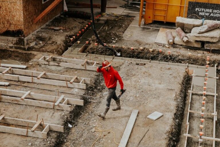 Contractor - man in red jacket and black pants walking on gray concrete stairs