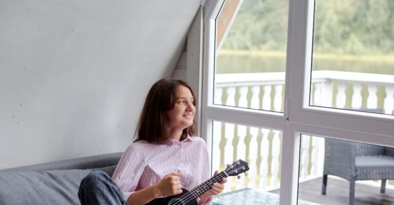 Attic Home - Smiling woman playing ukulele on couch in countryside house