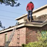 Roof Repair - a man standing on the roof of a house