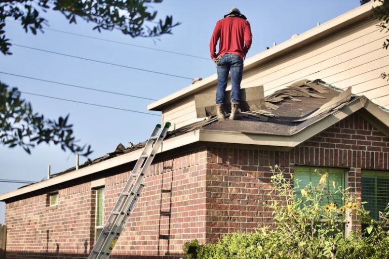 Roof Repair - a man standing on the roof of a house