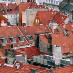 Attic Window - From above of aged dwelling building facades with attic windows on bright roofs in city