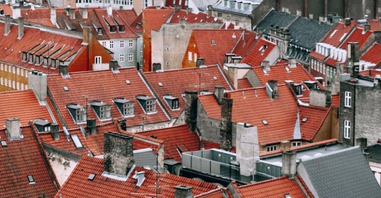 Attic Window - From above of aged dwelling building facades with attic windows on bright roofs in city