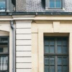 Attic Window - Exterior of aged residential building with mansard windows and French balconies on city street