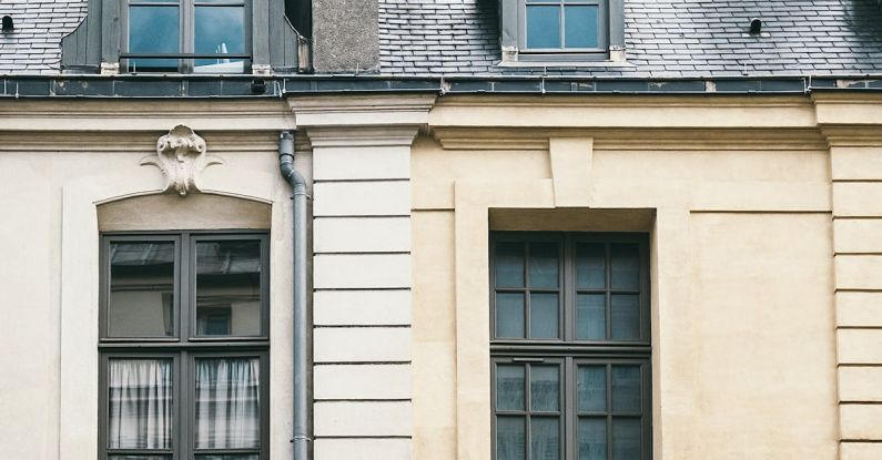 Attic Window - Exterior of aged residential building with mansard windows and French balconies on city street