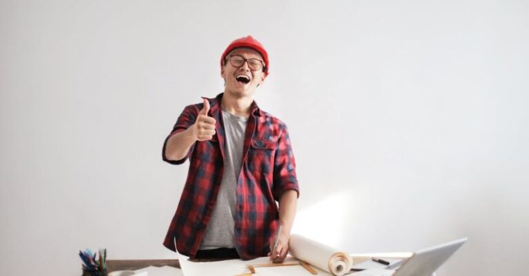 Inspectors - Laughing male constructor showing thumb up at working desk