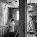 Renovation Budget - Two men are working on a wall in a room