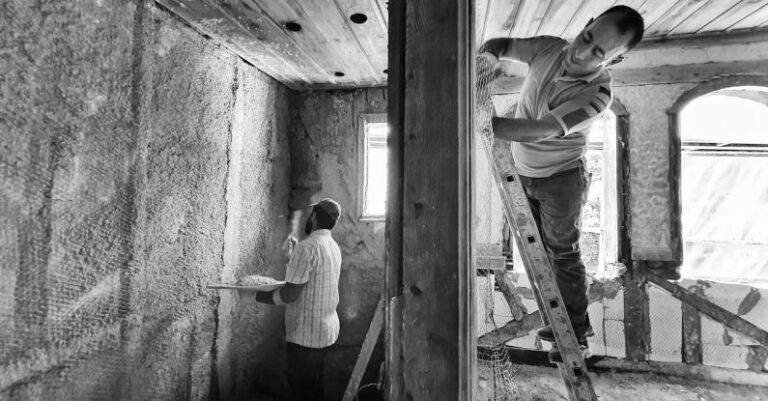 Renovation Budget - Two men are working on a wall in a room