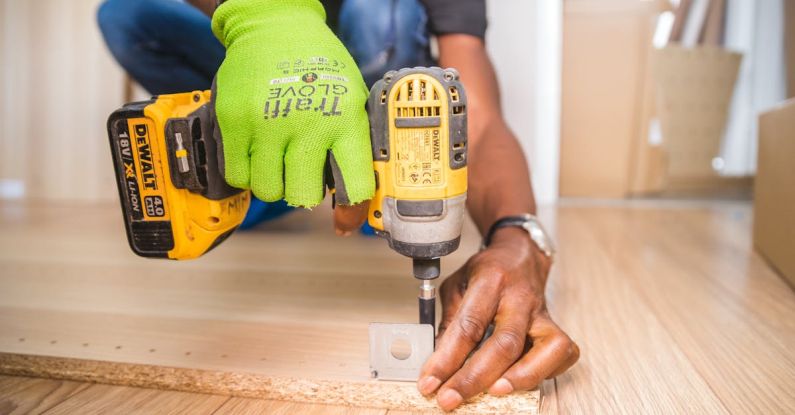 DIY Renovation - Person Using Dewalt Cordless Impact Driver on Brown Board