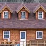 Attic Door - Dwelling building exterior with attic windows on roof between high mount and lake in daytime