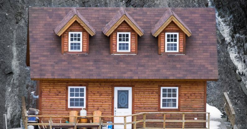 Attic Door - Dwelling building exterior with attic windows on roof between high mount and lake in daytime