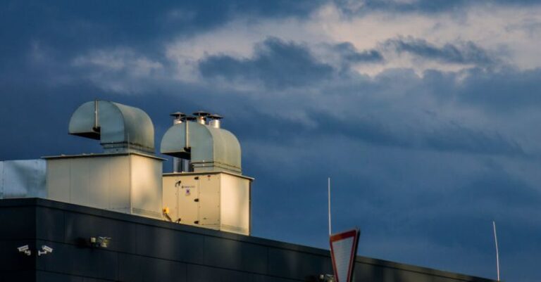 Roof Ventilation - Low angle of metal pipes of ventilation system located on rooftop of industrial building against cloudy sky